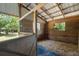 A well-equipped horse stall featuring wood paneling, windows, and a comfortable straw bedding area at 13719 Seminole Trl, Wimauma, FL 33598
