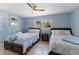 This bedroom features two beds with wooden frames, a ceiling fan, and a serene blue color scheme at 138 Pearl Ave, Sarasota, FL 34243