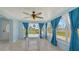 Light filled sunroom with a glass table, ceiling fan, and large windows with blue curtains at 156 Myakka Rd, Venice, FL 34293