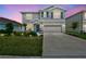 Two-story home featuring a manicured lawn, complemented by a two-car garage at twilight at 17330 Harvest Moon Way, Bradenton, FL 34211