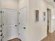 Hallway with neutral walls, tile floors and two white doors with black hardware and decorative wall art at 17725 Northwood Pl., Bradenton, FL 34202