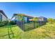 Fenced-in backyard featuring grass, mature landscaping, and screen enclosed lanai at 197 Villoresi Blvd, Nokomis, FL 34275