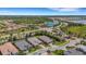 Panoramic aerial view of the community's entrance, lush landscapes, and serene lake and well-kept homes at 204 Corelli Dr, Nokomis, FL 34275
