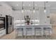 Stylish white kitchen featuring a large island with seating, stainless steel appliances, and pendant lighting at 204 Corelli Dr, Nokomis, FL 34275