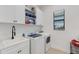 Well-lit laundry room with modern washer and dryer, sink, white cabinets, and a window at 204 Corelli Dr, Nokomis, FL 34275