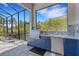 This outdoor kitchen features blue cabinets, stainless steel appliances, granite countertops, and brick patio space at 204 Corelli Dr, Nokomis, FL 34275