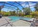 A screened-in pool features a spa, plenty of patio space, palm trees, and blue skies at 204 Corelli Dr, Nokomis, FL 34275