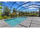 This screened-in pool and spa features a tanning ledge, with brick patio space, landscaping, and trees at 204 Corelli Dr, Nokomis, FL 34275