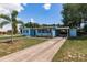 Light blue single-story home with a long driveway and mature landscaping on a sunny day at 22275 Belinda Ave, Port Charlotte, FL 33952