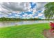 Picturesque backyard view with lush green lawn and a serene lake under a partly cloudy sky at 235 River Enclave Ct, Bradenton, FL 34212