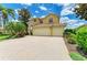 Stately yellow home showcasing a three-car garage, tile roof, paver driveway, and lush landscaping at 235 River Enclave Ct, Bradenton, FL 34212