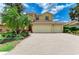 Exterior of a tan home with a red-tiled roof, a three-car garage, and manicured landscaping at 235 River Enclave Ct, Bradenton, FL 34212