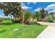 Beautifully landscaped front yard of a yellow two-story home with a well-manicured lawn and mature trees at 235 River Enclave Ct, Bradenton, FL 34212