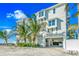 Three-story beach house featuring white exterior, palm trees, an open garage, and a private entrance at 2500 Gulf N Dr, Bradenton Beach, FL 34217