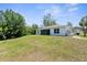 Backyard view of the house with a green lawn and trees at 2575 Johannesberg Rd, North Port, FL 34288