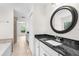 Bathroom vanity features dark countertops, white cabinets, and a stylish round mirror at 2575 Johannesberg Rd, North Port, FL 34288
