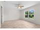 Bedroom with tile floors, a ceiling fan, and a large window offering a view of lush greenery at 2575 Johannesberg Rd, North Port, FL 34288