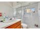 Bright bathroom featuring a glass shower enclosure, wood vanity, and neutral tile at 2729 Harvest Dr, Sarasota, FL 34240