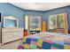 Spacious bedroom with blue walls, colorful quilt, and natural light from windows at 2729 Harvest Dr, Sarasota, FL 34240