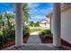 View of a brick entryway framed by white pillars and verdant landscaping at 2729 Harvest Dr, Sarasota, FL 34240