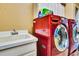 Well-organized laundry area with red washer/dryer, white cabinets, and a utility sink at 2729 Harvest Dr, Sarasota, FL 34240