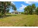 Expansive green backyard view featuring a white house in the distance surrounded by lush landscaping at 27519 Pasto Dr, Punta Gorda, FL 33983