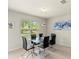 Dining area boasts modern glass table with black chairs and large window with blinds at 27519 Pasto Dr, Punta Gorda, FL 33983