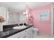 Bathroom with granite countertops, white cabinets, a large mirror, and pink walls at 307 White Oak Way, Sarasota, FL 34237