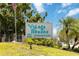 Community sign for Village Brooke Condominiums amidst lush landscaping with a bright blue sky and sunny Florida backdrop at 3269 Beneva Rd # 103, Sarasota, FL 34232