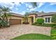 Charming tan home with a brick driveway, a tile roof, and lush landscaping with palm trees at 4818 88Th E St, Bradenton, FL 34211
