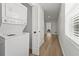 A bright hallway leads past a new washer/dryer combo and has hardwood floors, white walls, and natural light at 515 N Osprey Ave, Sarasota, FL 34236