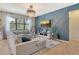 Stylish living room with a blue accent wall, large sectional sofa, and a modern chandelier, perfect for relaxation and entertainment at 5968 Snowy Egret Dr, Sarasota, FL 34238