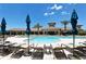 Stunning community pool with a clubhouse, lounge chairs, and blue umbrellas at 5968 Snowy Egret Dr, Sarasota, FL 34238