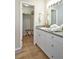 Bright bathroom featuring a granite countertop, white cabinets, and a walk-in closet with wooden floors at 6157 Midnight Pass Rd # E73, Sarasota, FL 34242