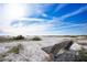 A sandy beach featuring a wooden bench under a clear blue sky, perfect for relaxation at 6157 Midnight Pass Rd # E73, Sarasota, FL 34242