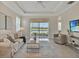 Bright living room with tile floors, neutral furniture, tray ceiling, and sliding glass doors with lake views at 635 Chipper Dr, Sun City Center, FL 33573