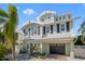 Charming two-story home with a manicured lawn, a garage, and coastal architectural details at 704 Gladiolus St, Anna Maria, FL 34216