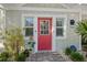 Charming home entrance featuring a vibrant red door, decorative plants, and well-maintained landscaping for curb appeal at 704 Gladiolus St, Anna Maria, FL 34216