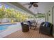 Covered patio with lounge furniture overlooking the pool and tropical landscape for relaxing and entertaining at 704 Gladiolus St, Anna Maria, FL 34216