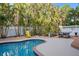 Lush backyard with a sparkling blue private pool, comfortable lounge chair, and ping pong table on patio at 704 Gladiolus St, Anna Maria, FL 34216