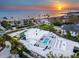 Stunning aerial view of a modern white home with a pool, beachfront access and sunset views at 7647 Sanderling Rd, Sarasota, FL 34242