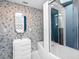 Chic bathroom with blue patterned walls, modern vanity, and a glass-enclosed shower-tub combination at 7647 Sanderling Rd, Sarasota, FL 34242
