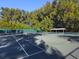 Well-maintained tennis court surrounded by tall trees, providing a serene and private playing environment at 7647 Sanderling Rd, Sarasota, FL 34242