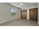 Empty bedroom featuring wood-style tile flooring, a window and closet doors at 791 Saint Judes Dr N, Longboat Key, FL 34228