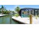Backyard view features the screened pool with a canal, vegetation, and dock in view at 791 Saint Judes Dr N, Longboat Key, FL 34228