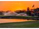 Scenic golf course view at sunset, featuring lush green grass, sprinklers, and a tranquil pond at 834 Springwood Cir, Bradenton, FL 34212