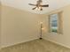 Cozy bedroom featuring carpet floors, neutral walls, ceiling fan, and large window at 9022 Coachman Dr, Venice, FL 34293