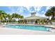 Inviting community pool with plenty of seating surrounded by palm trees and a clubhouse at 9022 Coachman Dr, Venice, FL 34293