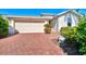 Paver driveway leading to a two-car garage, complemented by lush landscaping at 9022 Coachman Dr, Venice, FL 34293