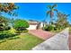 Inviting single-story home with a brick driveway, lush lawn, and mature palm trees at 9022 Coachman Dr, Venice, FL 34293